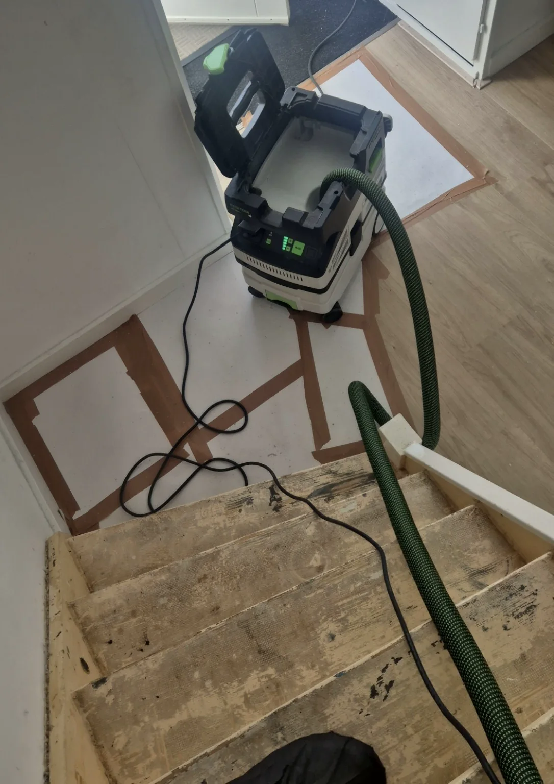 Kale houten trap met professionele stofafzuiger tijdens het schuren